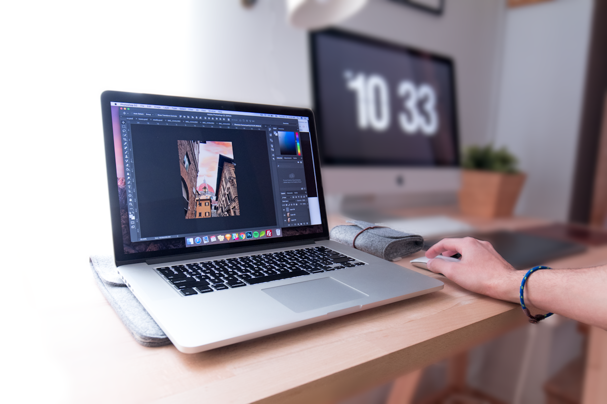 A designer working on a laptop at a wooden desk